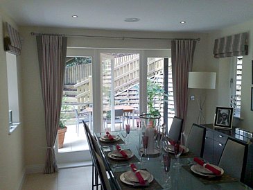 Dining area with curtains on a metal pole and Roman Blinds to the side window